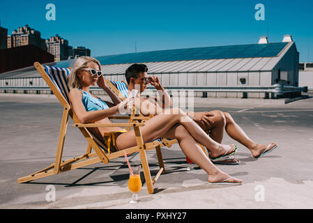 Coppia giovane rilassarsi sui lettini relax su parcheggio Foto Stock