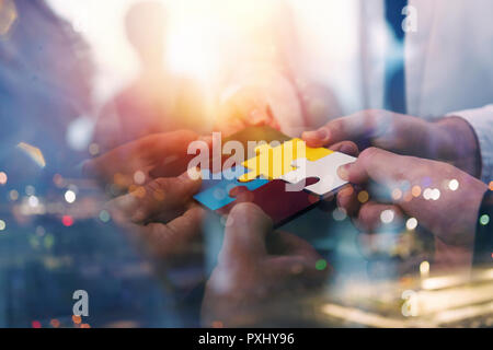 La gente di affari unire i pezzi del puzzle in ufficio. Concetto di partnership e il lavoro di squadra. doppia esposizione con effetti di luce Foto Stock