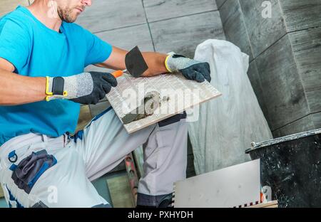 Il contraente in bagno di installare nuove di zecca le piastrelle di ceramica. Bagno rimodellamento osseo. Foto Stock