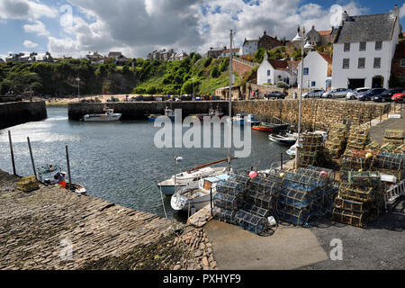 Il molo di pietra pareti a Crail porto con barche da pesca e astice trappole e scogliera con spiaggia a Crail Fife Scozia UK Foto Stock