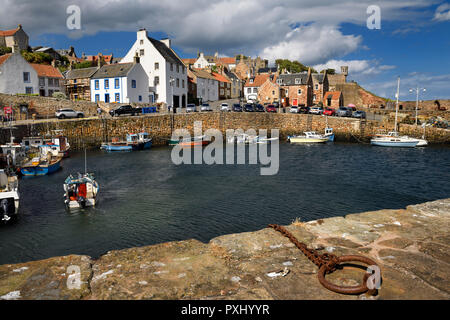 Pescatore sulla barca ritorna a Crail Harbour con pilastri di pietra e di ferro ad anello di ormeggio sul Mare del Nord Scozia UK Foto Stock