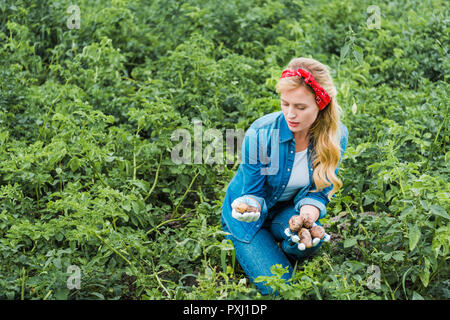 Attraente agricoltore guardando le patate in un campo a livello di azienda Foto Stock