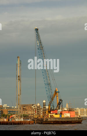Enormi gru e trapanare su uno dei molti nuovi sviluppi, rigenerazione di spazi disponibili e preparare le basi, lungo il fiume Tamigi, London REGNO UNITO Foto Stock