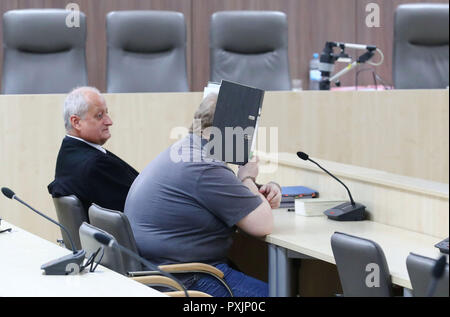 Gera, Germania. 23 Ott, 2018. La convenuta, che nasconde la sua faccia dietro un file, si siede accanto al suo difensore Stephan Rittler nell'aula del tribunale distrettuale. Il 66-anno-vecchio è accusato di aver ucciso un dieci-anno-vecchia ragazza di Weimar in agosto 1991. Solo dopo 27 anni la criminalità potrebbe essere risolto. Credito: Bodo Schackow/dpa-Zentralbild/dpa/Alamy Live News Foto Stock