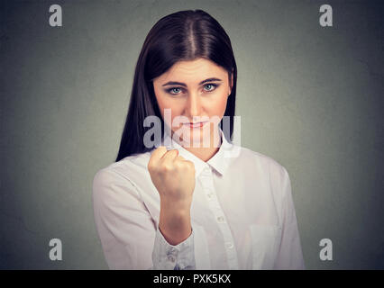 Giovani brunette formale che indossa una camicia bianca e il pugno mostrando in modo aggressivo in telecamera Foto Stock