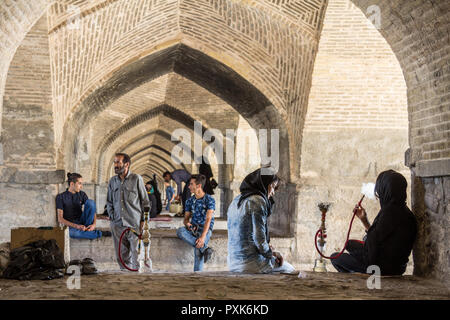 ISFAHAN, IRAN - 20 agosto 2016 : giovani iraniani la raccolta di sotto Si o Seh Pol ponte di fumare narghilè e utilizzando gli smartphone. Si o Seh Pol è uno dei Foto Stock