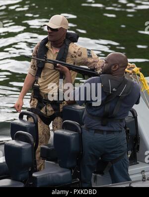 Porto di Spagna, Trinidad - un membro del Maritime tattico Gruppo Operatori (MTOG) osserva mentre un membro della Trinidad e Tobago Coast Guard (TTCG) fornisce la copertura per il partito di imbarco durante l'imbarco di formazione presso la base TTCG in Chaguaramas, Trinidad come parte di esercizio TRADEWINDS 17 il 8 giugno 2017. (Forze canadesi combattere la fotocamera Foto Stock