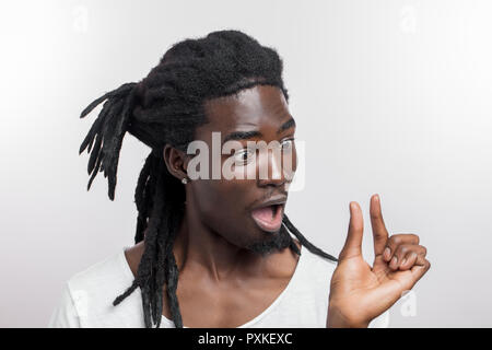 Sorpreso maschio africana con dreadlocks mostra un piccolo segno con la mano Foto Stock