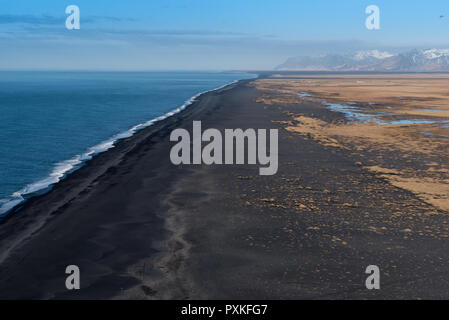 Guardando ad ovest da Dyrholaey al vasto sabbia nera vulcanica beach con le montagne sullo sfondo Foto Stock