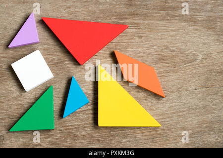 Tangram Straggled puzzle attendere per completare la forma su uno sfondo di legno Foto Stock