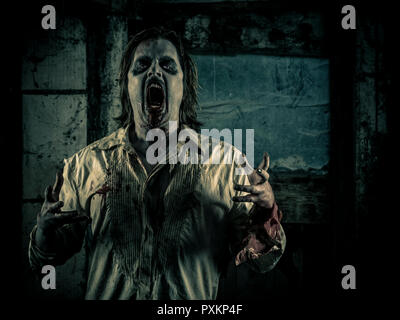 Foto di un affamato zombie staring a voi in una buia stanza spaventoso. Foto Stock