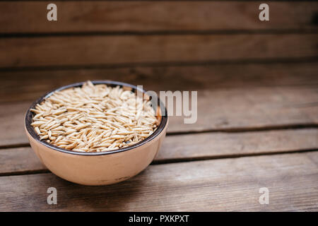 Vista dall'alto una ciotola di cereali di avena su uno sfondo di legno, alimenti naturali Foto Stock