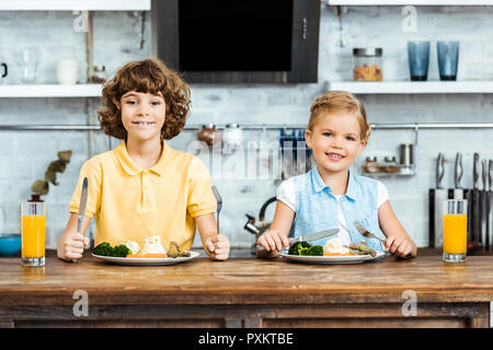Adorabili bambini mangiare le verdure e sorridente in telecamera in cucina Foto Stock