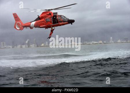 Petty Officer di terza classe Bryan Evans, una guardia costiera Stazione aria Miami rescue nuotatore, conduce una caduta libera distribuzione da un MH-65 Delfino elicottero a est di Miami Beach il 6 giugno 2017. (Coast Guard Foto Stock