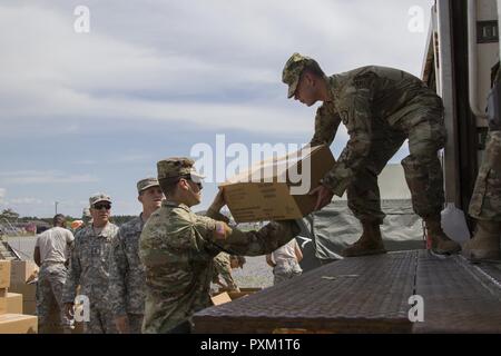 Stati Uniti Army Spc. Hunter Lundin, Charlie Company, 572nd ingegnere vigili del Battaglione, 86a brigata di fanteria combattere Team (montagna), passa una scatola di pasti a Spc. Evan Goldring, sede del Quartier Generale Azienda, 186th brigata battaglione di supporto, a Fort Drum, N.Y., 9 giugno 2017. La 86IBCT (MTN) condotto una warfighter esercizio per la loro formazione annuale. Foto Stock