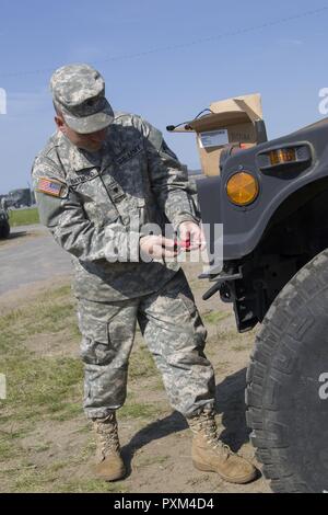 Stati Uniti Army Spc. Kale Raymond, Echo Company, 186th brigata battaglione di supporto, 86a brigata di fanteria combattere Team (montagna), Vermont Guardia nazionale, sostituisce un Humvee è il faro a Fort Drum, N.Y., 10 giugno 2017. Raymond e SPC. Kyle Spaulding siete sono solo la meccanica di supporto del 86º IBCT (MTN) durante un esercizio warfighter condotta per formazione annuale. Foto Stock