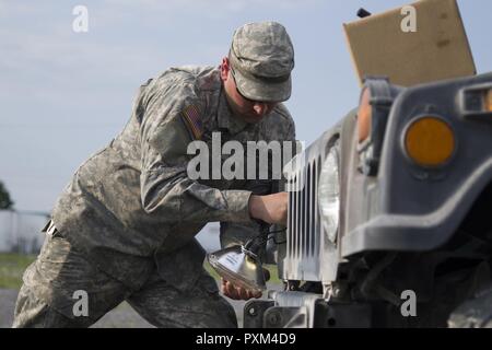 Stati Uniti Army Spc. Kyle Spaulding siete, Echo Company, 186th brigata battaglione di supporto, 86a brigata di fanteria combattere Team (montagna), Vermont Guardia nazionale, sostituisce un Humvee è il faro a Fort Drum, N.Y., 10 giugno 2017. Spaulding siete Spc. Kale Raymond sono la sola meccanica di supporto del 86º IBCT (MTN) durante un esercizio warfighter condotta per formazione annuale. Foto Stock