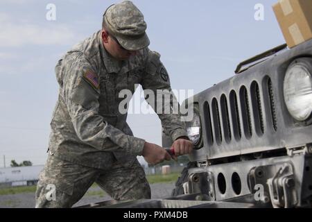 Stati Uniti Army Spc. Kyle Spaulding siete, Echo Company, 186th brigata battaglione di supporto, 86a brigata di fanteria combattere Team (montagna), Vermont Guardia nazionale, sostituisce un Humvee è il faro a Fort Drum, N.Y., 10 giugno 2017. Spaulding siete Spc. Kale Raymond sono la sola meccanica di supporto del 86º IBCT (MTN) durante un esercizio warfighter condotta per formazione annuale. Foto Stock