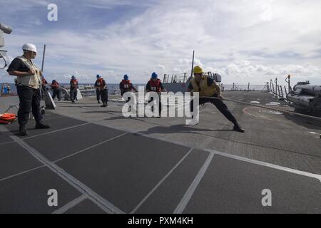 Sul mare del sud della Cina (9 giugno 2017) i gestori di linea a bordo Arleigh Burke-class guidato-missile destroyer USS Sterett (DDG 104) heave intorno a una linea di trasporto di carichi secchi e munizioni nave USNS Richard E. Byrd (T-AKE 4) durante un rifornimento in mare. Sterett è parte della superficie Sterett-Dewey Action Group ed è il terzo gruppo di distribuzione che operano sotto il comando ed il controllo costrutto denominato 3a flotta in avanti. Stati Uniti 3a flotta operante in avanti offre opzioni aggiuntive per la flotta del Pacifico commander sfruttando le capacità del 3° e 7° flotte. Foto Stock