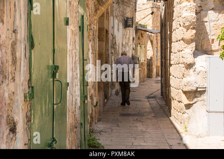 Il vecchio uomo visto da dietro, camminando attraverso le strade della storica città vecchia di Akko, Israele. Foto Stock