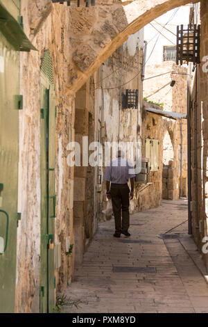 Il vecchio uomo visto da dietro, camminando attraverso le strade della storica città vecchia di Akko, Israele. Foto Stock