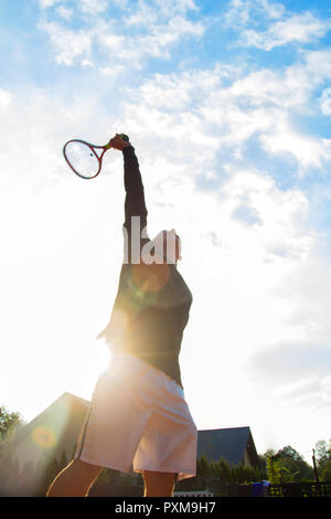 Giocatore di tennis professionista giocando una partita di tennis su una corte. Egli sta per colpire la palla con la racchetta. Foto Stock