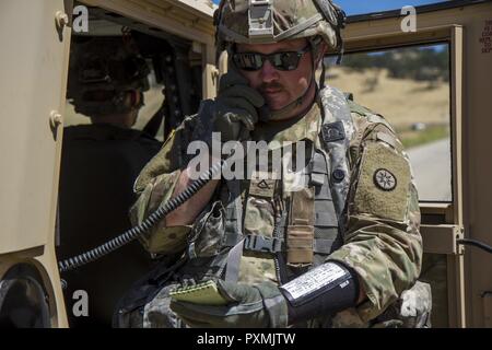 Stati Uniti Pfc dell'esercito. Matthew Dunn, 822nd distacco di trasporto al di fuori del Brockton, Massachusetts, chiamate in una 9 linea di evacuazione medica (MEDEVAC) per simulare un incidente per un improvvisato dispositivo esplosivo (IED) formazione sulla Fort Hunter Liggett, la California il 15 giugno 2017. IED formazione fa parte della 91a Divisione di formazione era il Guerriero Esercizio (WAREX) 91-17-03, un collettivo di piattaforma di formazione che prepara i soldati per combattere immergendoli in realistici scenari di combattimento; qui, Dunn può essere completamente preparati in caso di un vero e proprio attacco di IED. Foto Stock