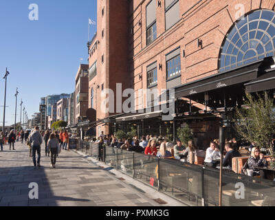 La Aker Brygge area nel centro di Oslo Norvegia ha molti ristoranti con vista del fiordo, posti a sedere esterni è essenziale in una giornata di sole, qui Olivia Foto Stock