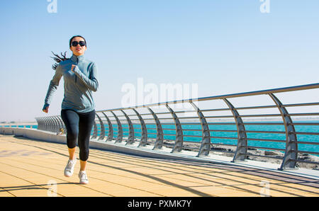 Ragazza che corre su di una passerella per un allenamento in riva al mare Foto Stock