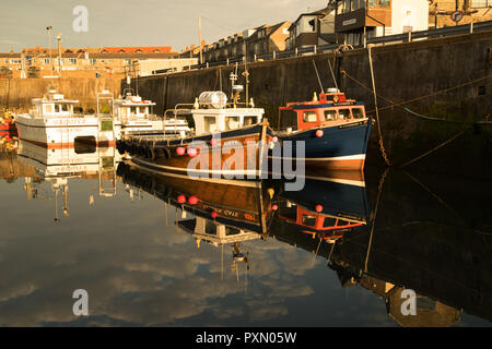 Le riflessioni di imbarcazioni da diporto in porto Seahouses, Northumberland, Inghilterra Foto Stock