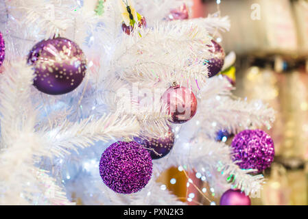 Viola alla moda, ultravioletto baubles colorate in bianco argento albero di Natale artificiale. Close up. Messa a fuoco selettiva, spazio di copia Foto Stock