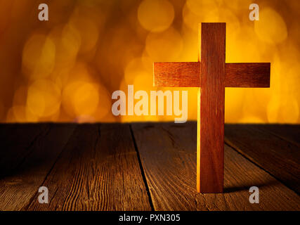 Cristiana croce di legno su blur flare luci e lo sfondo di legno Foto Stock