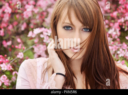 Bella ragazza in posa su fiori di primavera sullo sfondo Foto Stock