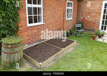 Un nuovo vuoto letto sollevata in un orto è riempita con il terreno pronto per piantare Foto Stock