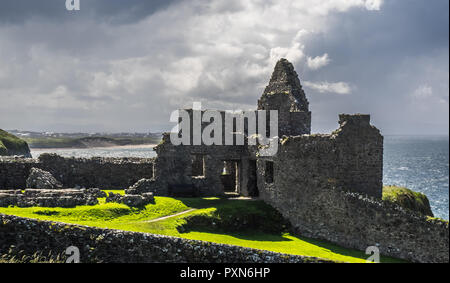 BUSHMILLS, NORTHER IRLANDA - Luglio 13, 2016 Dunluce Castle. .Le rovine del Dunluce Castle e si può vedere nella distanza rocce bianche beach. - Nord Foto Stock