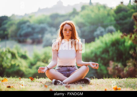 L'Italia, Verona, ritratto di donna redheaded facendo esercizi yoga su una collina Foto Stock