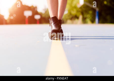 Le gambe di una donna che indossa stivaletti a camminare su una linea sul campo sportivo Foto Stock