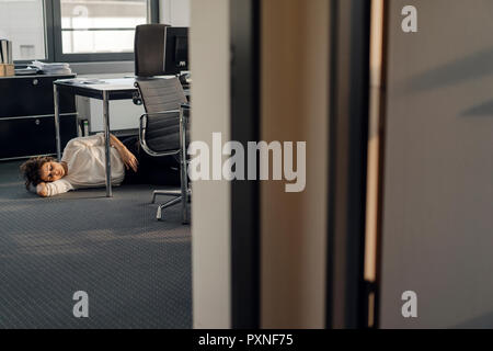 Stanco imprenditrice dormire sul pavimento sotto la scrivania Foto Stock