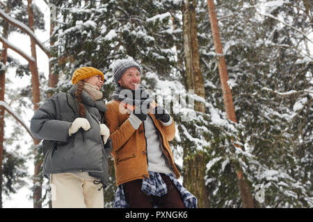 Allegro eccitato giovani amici con gli zaini a piedi nella foresta di inverno e di discutere il percorso di viaggio Foto Stock