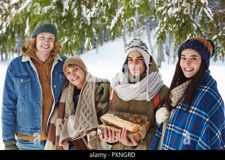 Ritratto di due belle coppie giovani in posa nevoso inverno foresta sotto permanente di abete e sorridente alla fotocamera, spazio di copia Foto Stock