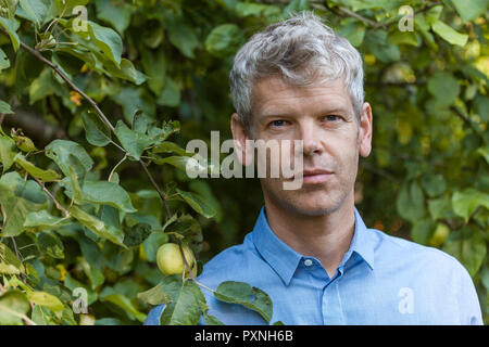 Ritratto di uomo maturo con i capelli grigi in giardino Foto Stock