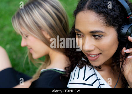 Due amiche in un parco e ascolto di musica Foto Stock