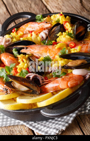 Deliziosa paella spagnola con frutti di mare e pesce di close-up in una padella sulla tavola verticale. Foto Stock