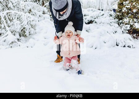 Elegante felice giovane famiglia passeggiate con il bambino sulla strada invernale, mamma, papà, bambino Foto Stock