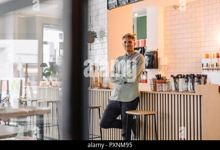 Giovane uomo che lavora nella sua start-up cafe, ritratto Foto Stock