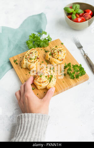 Donna di mano tenendo sticky bun con feta, crema di formaggio, pancetta e prezzemolo Foto Stock