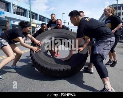 L'Alaska Air National Guard team Arctic custodi partecipa a un pneumatico-roll sfida durante il 2017 giochi di eroi Giugno 17, 2017 come parte di ancoraggio per il centro cittadino di Solstice Festival. Due membri rotolare il pneumatico prima di tutto il team è stato richiesto per capovolgere il pneumatico torna alla linea di partenza. Foto Stock