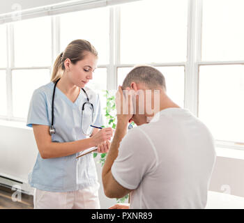 Gli uomini con il medico avente un problema della testina Foto Stock