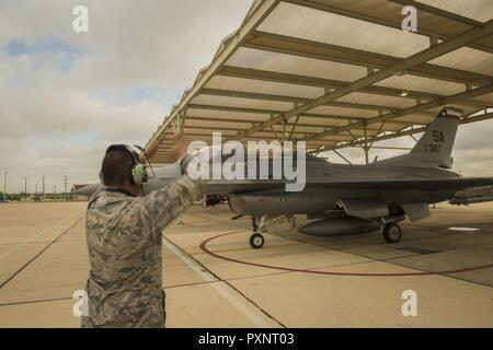 Stati Uniti Air Force Staff Sgt. Saul Huerta, 149gruppo Manutenzione, Air National Guard, esegue il marshalling di un F-16 Fighting Falcon sulla pista di rullaggio a base comune San Antonio-Lackland, Texas, 15 giugno 2017. La principale missione federale del 149Fighter Wing è di addestrare i piloti a impiegare il F-16 cellula Foto Stock