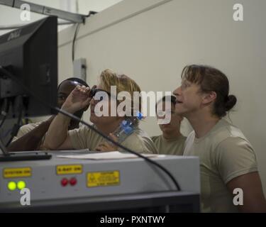 Stati Uniti Air Force avieri con il 8° Expeditionary Aria Mobilità Squadron scrutare il bagaglio per articoli proibiti su un monitor a screening bagagli check point di Al Udeid Air Base, Qatar, 14 giugno 2017. Il aviatori sono migliorando la loro conoscenza su precauzioni di sicurezza per l'ispezione del bagaglio personale che passano attraverso il terminal passeggeri. Foto Stock